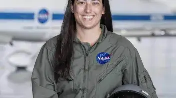 Avery Carifa smiles in a green NASA jumpsuit and pilot helmet