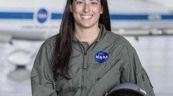 Avery Carifa smiles in a green NASA jumpsuit and pilot helmet