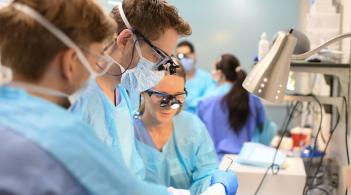 three students in scrubs learn in a clinical lab