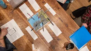 A view of a table with papers and pencils and students working