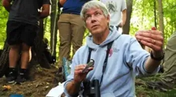 Professor Allan Strong holding a bird and explaining something to a group of students