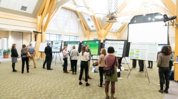 People standing in a large room with academic research posters