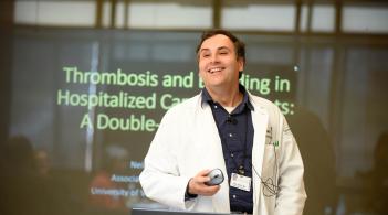 A presenter speaking in front of a slideshow at a medical Grand Round