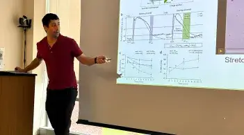 Researcher standing and presenting their findings on a large projection screen.