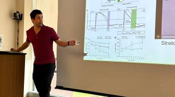 Researcher standing and presenting their findings on a large projection screen.