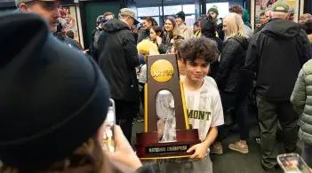 A young fan holds the NCAA Men's Soccer Championship trophy after the UVM Catamounts return home with it.