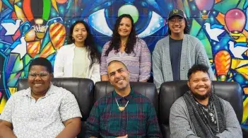 MCSC staff smiling infront of the colorful mural