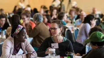people at a conference, seated at round tables, talking