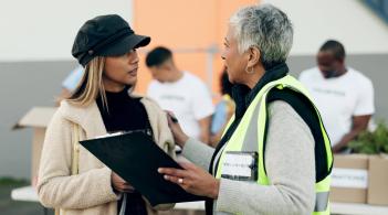 Person holding a clip board speaks to another person 