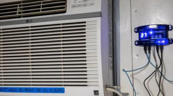 an air conditioner in a wall, next to a fancy thermostat