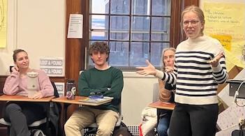 A teacher stands and talks to her class