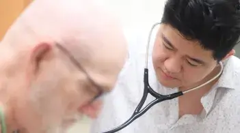 Provider using stethoscope to monitor a patients chest