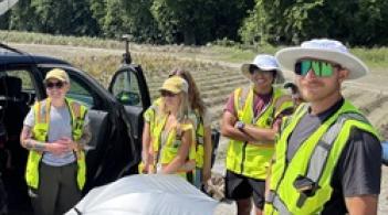 A group of people wearing yellow safety vests smiling 