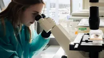 Scientist looking through microscope lenses