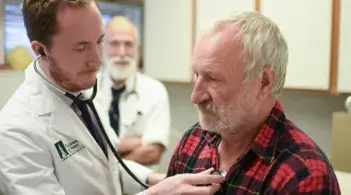 medical student listens to patient's lungs