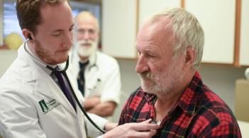 medical student listens to patient's lungs