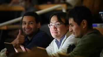 three people enjoying a lecture and one thumbs up
