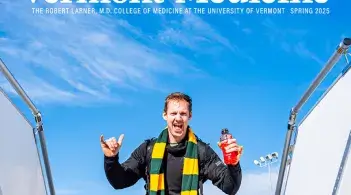 Man in a green and yellow striped scarf making a hang loose sign as he tops out the stairway at airport