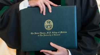 close up of hands holding a green diploma 