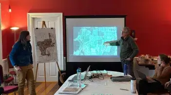 Three people looking at a map of a property on a large screen.