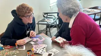 Student and older adult smiling at each other