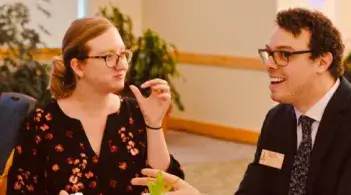 two people sitting at a table and talking