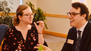 two people sitting at a table and talking