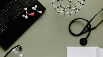 a laptop, molecule diagrams and stethoscope on a table