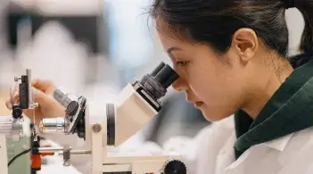 student looking into microscope in lab