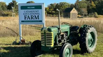 catamount education farm sign next to an antique tractor