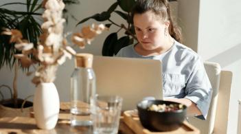A young woman with Down Syndrome works at a laptop