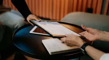 Someone hands another person a clipboard with a form to fill out