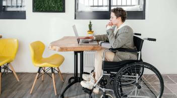 A white woman with short nut-brown hair sits in a wheelchair at a table