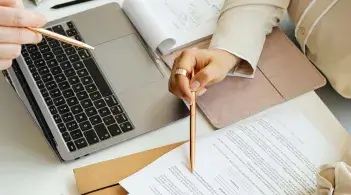 People gather around a table to work on a document at a laptop