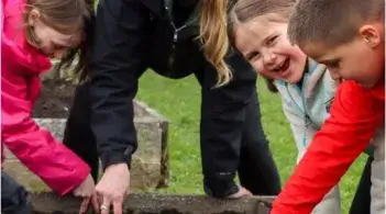 smiling woman and children planting seeds outside
