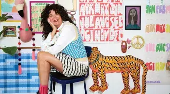 a person sits on a stool surrounded by colorful artwork