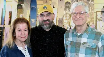 three people stand in front of a rack of skis