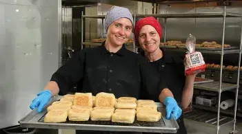 two people hold loaves of bread in a kitchen