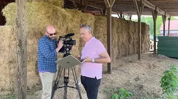 two men working with a video camera in a barn