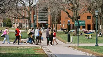 A group of people walking on a sidewalk beside a building