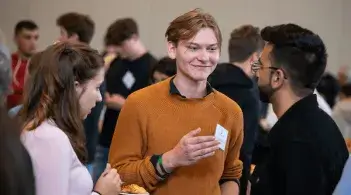 Students talking and socializing at an indoor event.