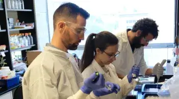 three people in lab coats working in a lab