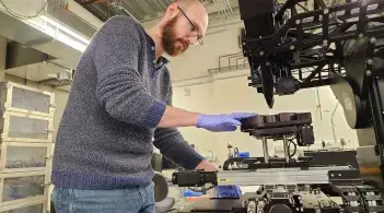 Man working UVM graduate student Kenneth Shepherd Jr. measures thickness of materials while working with an ellipsometer in the Characterization Lab in Discovery. The lab, created through a gift from GlobalFoundries, is integral to semiconductor research at UVM.