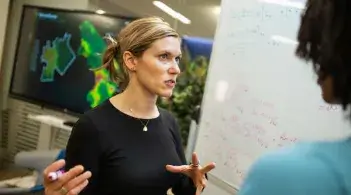 People talking in front of a whiteboard and digital display