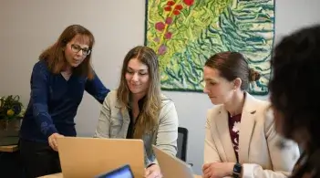 four people looking at a laptop
