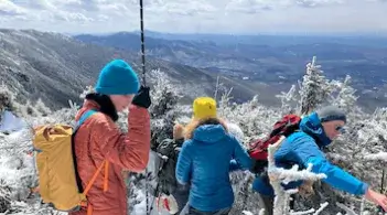 a group of people in colorful winter gear with measuring tools on top of a snowy mountain