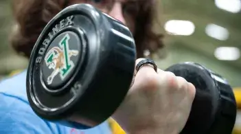 Close up of dumbbell in hand of student performing bicep curl.