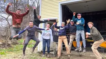 Students jumping in the air in a moment of levity during an outing to help local residents cleanup after a flood.