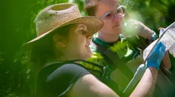 two people inspect a creature captured in a net