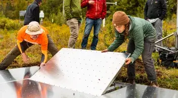 two people place a metal panel in place on a large sensor platform
